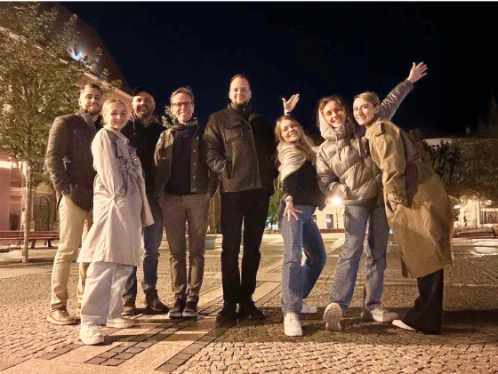 Eight Object First team members posing outdoors at night standing casually and smiling.
